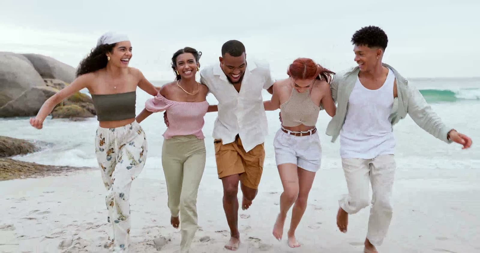 A group of friends laughing together as they walk along the beach
